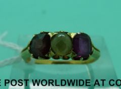 A yellow metal ring set with a sapphire exhibiting chatoyancy effect and two red stones (size L)