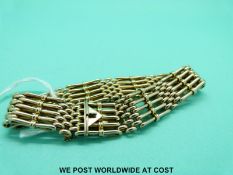 A yellow metal gate bracelet marked 9 with triangular clasp (23.
