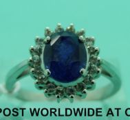 A 14ct white gold ring set with an oval cut sapphire surrounded by diamonds (Size R)