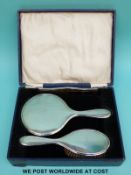 A cased three piece George V hallmarked silver dressing table set comprising hand mirror,