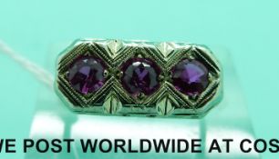 A white metal ring marked 18k set with three pink sapphires (size K)
