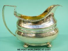 A Georgian hallmarked silver cream jug with gilt wash interior raised on four ball feet,