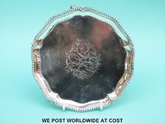 A Georgian hallmarked silver salver with shaped and beaded edge raised on three ball and claw feet,