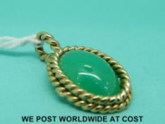 A yellow metal pendant set with a jadeite cabochon