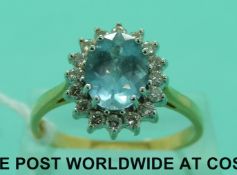 An 18ct gold ring set with an oval aquamarine surrounded by diamonds (size T)