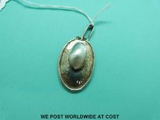 A white metal hammered pendant set with a large blister pearl to the centre