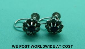 A pair of 9ct white gold earrings set with a round sapphire surrounded by diamonds in a floral