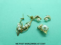 A yellow metal pendant marked 14k set with a pearl surrounded by dolphins,