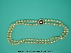 A double strand of cultured pearls with a 9ct gold clasp set with a garnet,