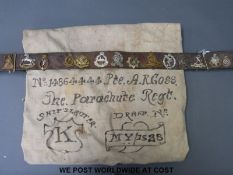 A leather military belt with sixteen military cap badges attached to include Artists,