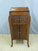 A floor standing gramophone with internal horn and storage space below,