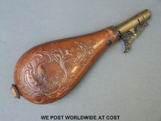 A brown leather shot flask with embossed decoration of bird and flowers and brass mount.