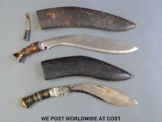 Two Gurkha kukri knives, one with inlaid horn handle and brass lion's head pommel,