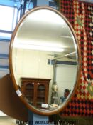 An oak framed bevelled glass oval mirror,