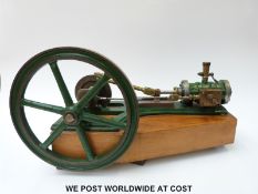 A horizontal stationary live steam engine mounted on a wooden base with 26cm diameter flywheel and