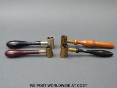 Four brass shot and powder measures with turned wooden handles.