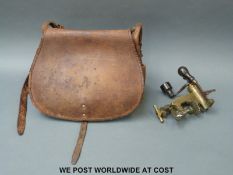 A brass cartridge loading tool with turned wooden handles and a vintage brown leather cartridge bag.