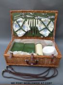 A retro picnic hamper with china plates, metal cutlery, thermos, leather straps etc.