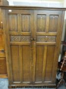 An oak Old Charm style linen fold bedroom suite comprising two wardrobes,