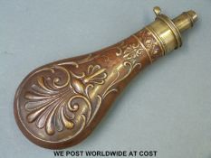 Copper powder flask with embossed scrolling decoration and brass mount.