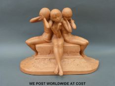 A terracotta model of three children sitting on a plinth,