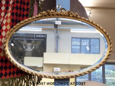 An oval mirror with bevelled glass,