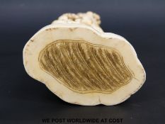 A Japanese Meiji period carved ivory okimono of a man with a performing monkey above his head and a