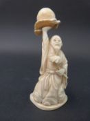 A Japanese carved ivory figure of a man holding fruit aloft,