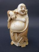 A Japanese Meiji period carved ivory Buddha carrying a sack over his shoulder, signed to base,