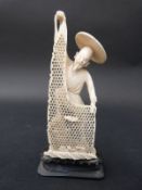 An early 20thC carved ivory figure of a fisherman with net on ebony base,