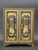 A Japanese lacquer cabinet all over decorated in gilt with figures, buildings and insects,