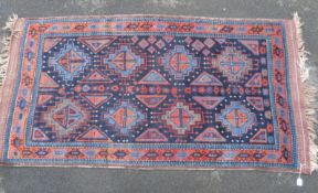 An Afghan rug with blue and orange decoration on deep blue ground.