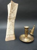 A carved African bone and a brass chamber stick