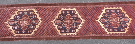 An Afghan runner with geometric decoration on deep red ground.