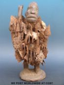 An African tribal figure with glass eyes and jagged metal decoration,