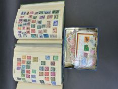 A pair of all world stamp albums and a tin of stamps including 1946 Victory omnibus stamps