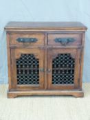 An Eastern hardwood two door cabinet with metal grille fronts (W90 x D41 x H87cm)