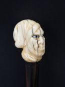 A 19thC swordstick handle with carved marine ivory finial in the form of a man's head with glass