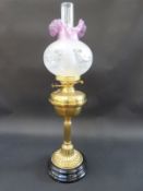 A brass oil lamp with engraved pink frilled glass shade,