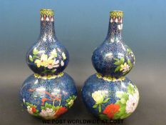 A pair of Chinese cloisonne double gourd vases with floral decoration on a blue ground,
