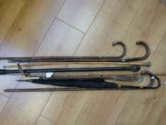 A collection of walking sticks with silver tips, an umbrella with 9ct gold trim,