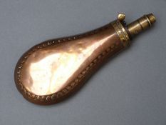 Copper and brass powder flask with embossed rivet style decoration, 19cm long.