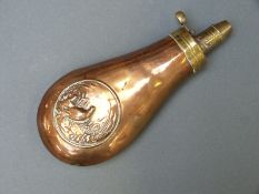 A copper and brass powder flask with embossed decoration of partridge in a corn field, 18cm long.