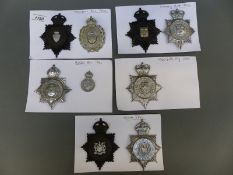 Police helmet plates and badges mounted on card relating to Wigan, Wakefield City, Grimsby,