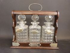 An oak three bottle tantalus with silver plate fittings