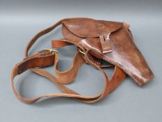A brown leather pistol holster and belt with brass fittings.