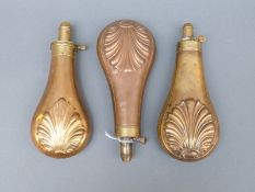 Three copper and brass powder flasks with embossed shell decoration, one stamped 'patent',