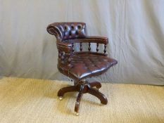 A red leather button back captain's chair on brass castors