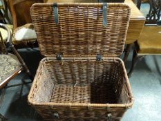 A wicker basket or large hamper with leather straps and looped wicker handles (H45 x L75 x W47cm)