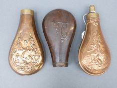 Three copper and brass powder flasks all with embossed decoration of hunting scenes, largest 17.